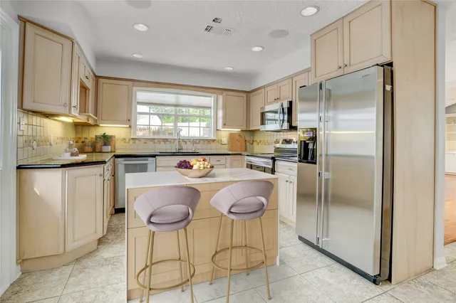 a kitchen with kitchen island granite countertop a refrigerator a stove a sink and white cabinets with wooden floor