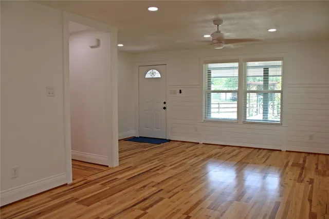 a view of an empty room with wooden floor and a window