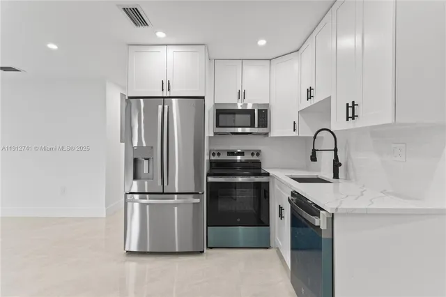 a kitchen with stainless steel appliances granite countertop a refrigerator sink and microwave