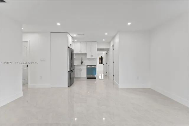 a view of a kitchen with refrigerator and white cabinets