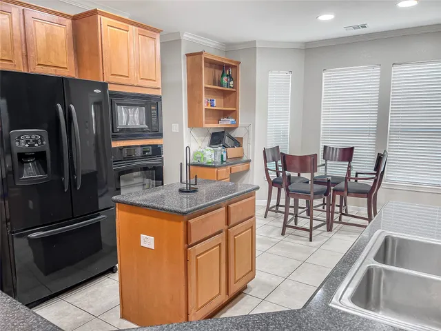 a kitchen with stainless steel appliances granite countertop a table chairs and a refrigerator