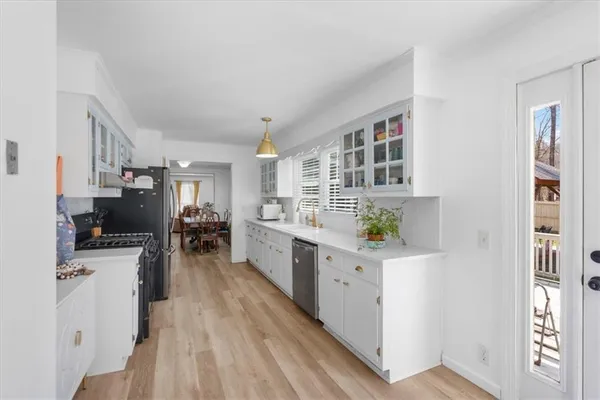 a kitchen with stainless steel appliances a stove top oven a sink a refrigerator white cabinets and wooden floor