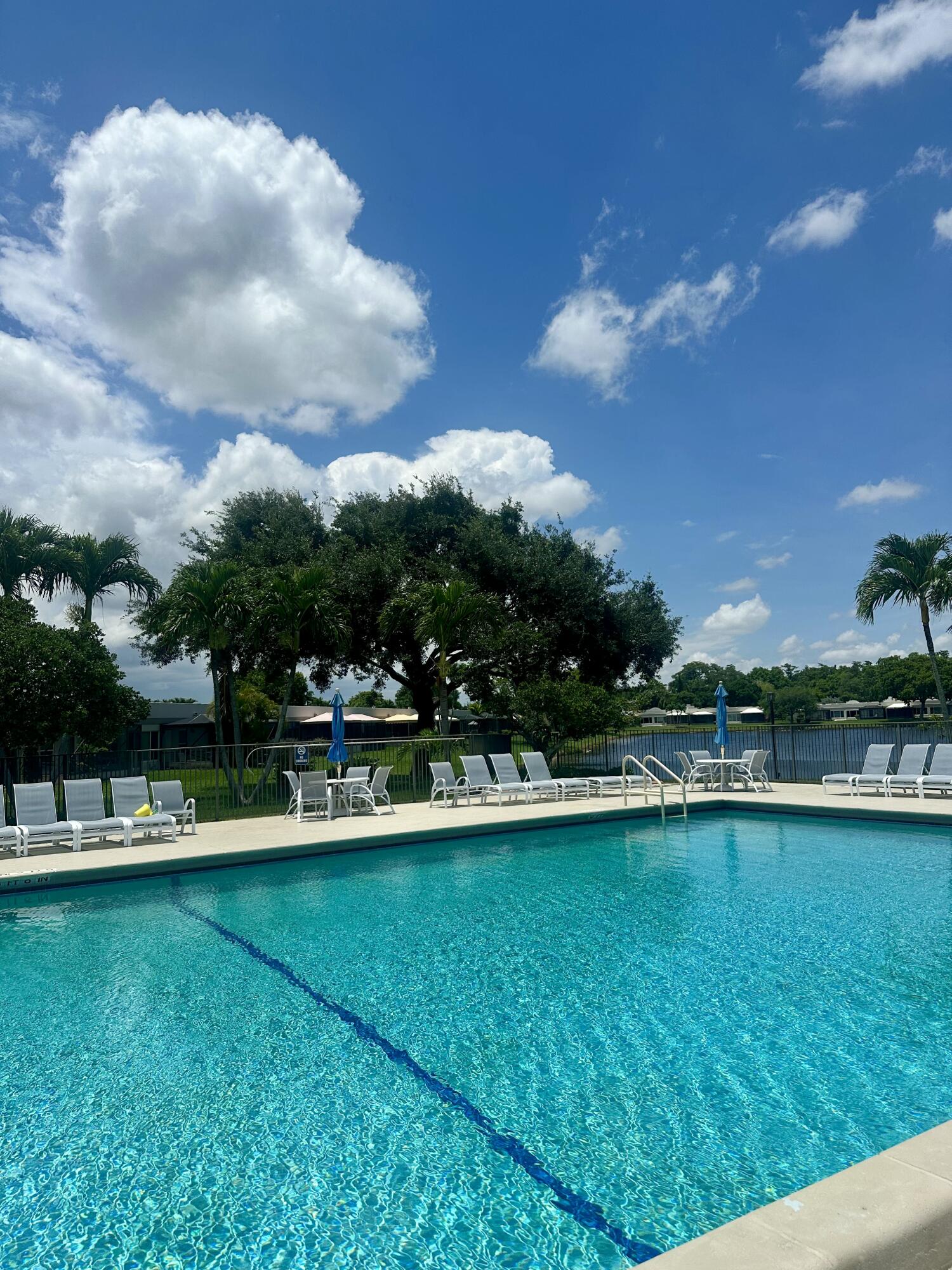 18900 Stewart Circle, Unit 7 Boca Raton, FL 33496 - Photo 10 of 23 a view of a lake with lawn chairs and large trees