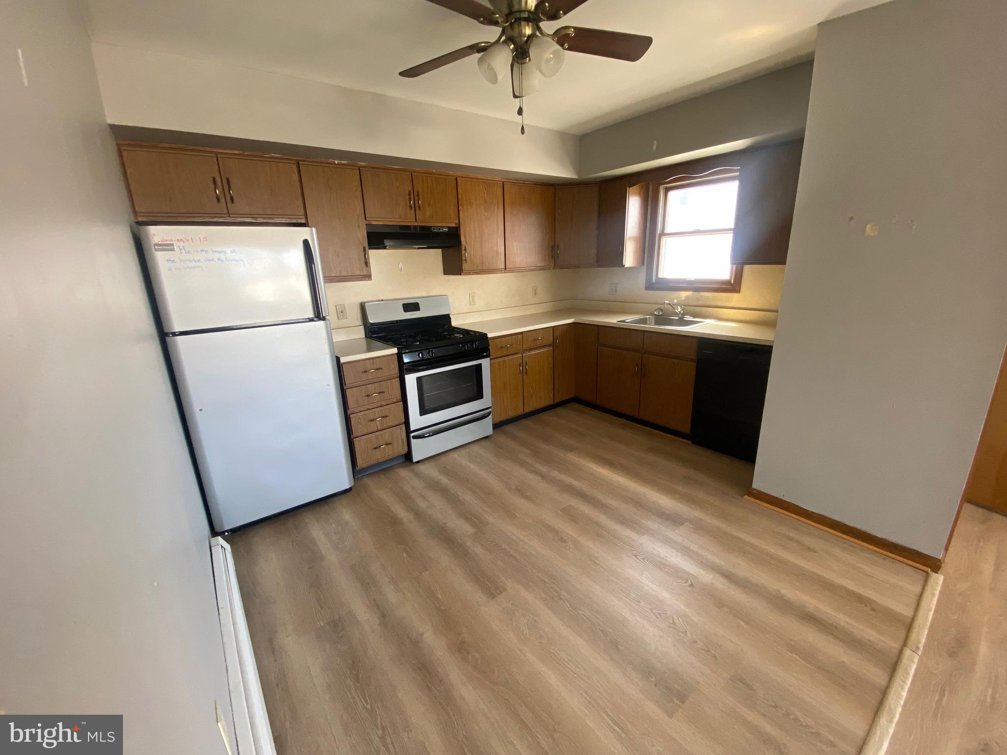 a kitchen with granite countertop a refrigerator a sink a stove and cabinets