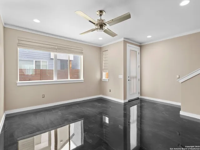 a view of an empty room with wooden floor and a ceiling fan