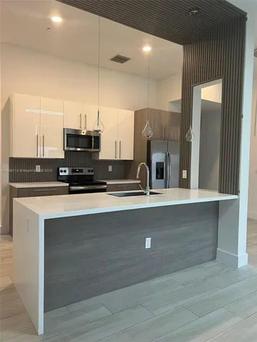 a view of kitchen with stainless steel appliances granite countertop a sink and a refrigerator