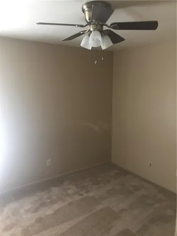 an empty room with a fan & a ceiling fan