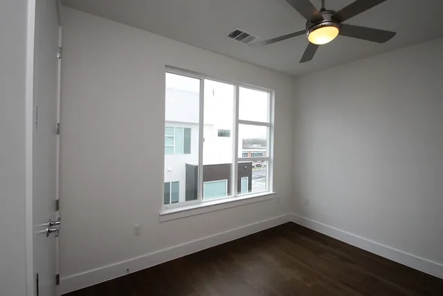 an empty room with a window and ceiling fan