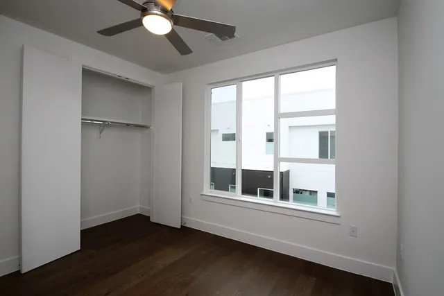 a view of an empty room with a window and wooden floor
