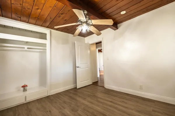 a view of an empty room with wooden floor and white walls