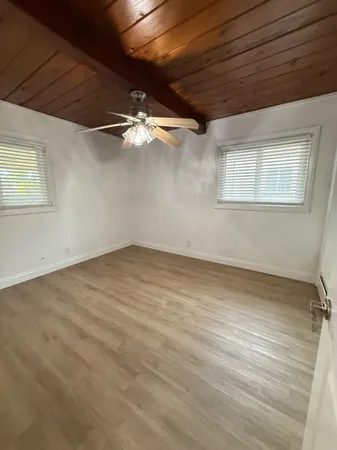 an empty room with a chandelier fan and windows