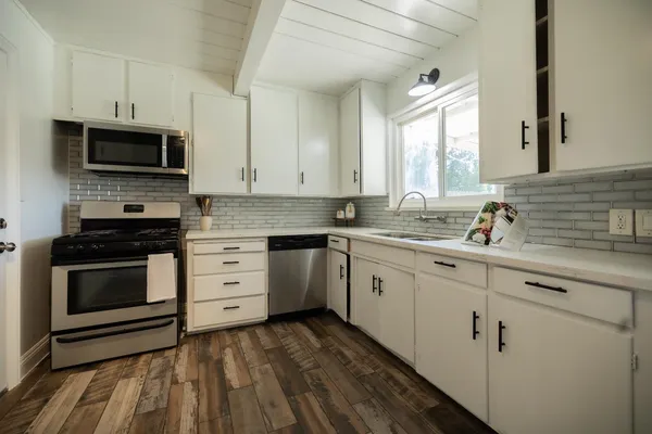 a kitchen with granite countertop white cabinets stainless steel appliances and a sink