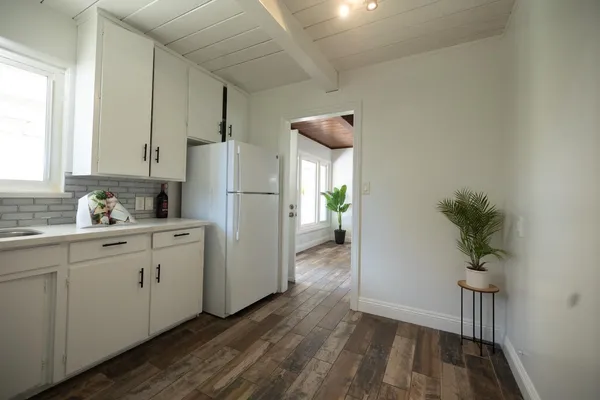 a kitchen with white cabinets and wooden floors