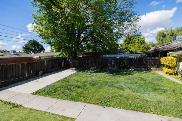 a view of a backyard with wooden fence and a bench