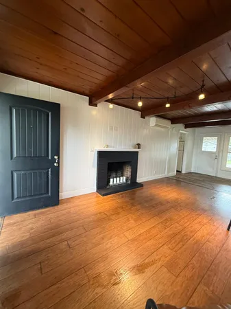 a view of an empty room with wooden floor and a fireplace