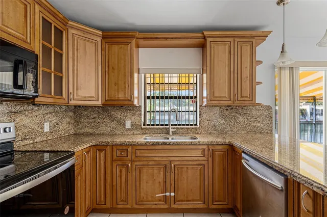 a kitchen with granite countertop cabinets stainless steel appliances a sink and a window