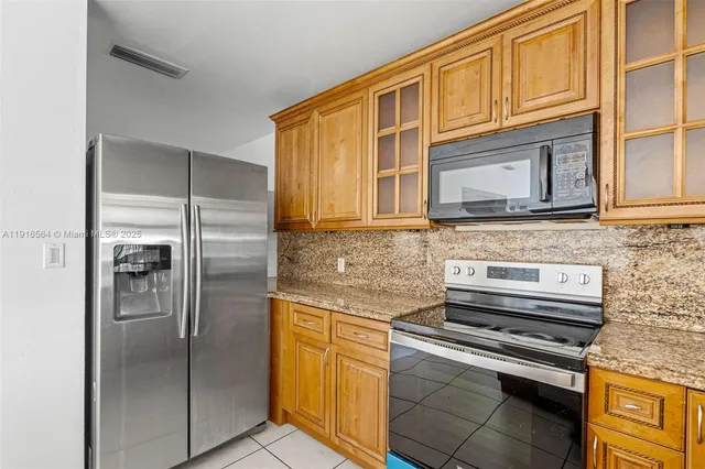 a kitchen with stainless steel appliances granite countertop a refrigerator and a stove top oven