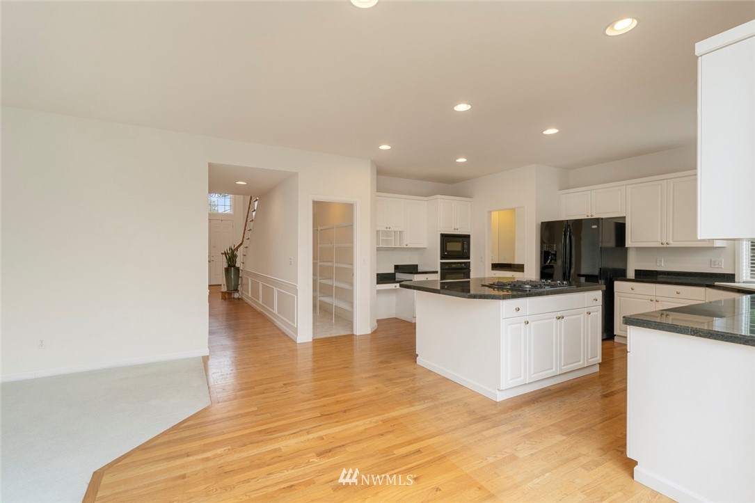 3914 207th Place Southeast Bothell, WA 98021 - Photo 8 of 21 a large white kitchen with kitchen island a sink a stove and a refrigerator