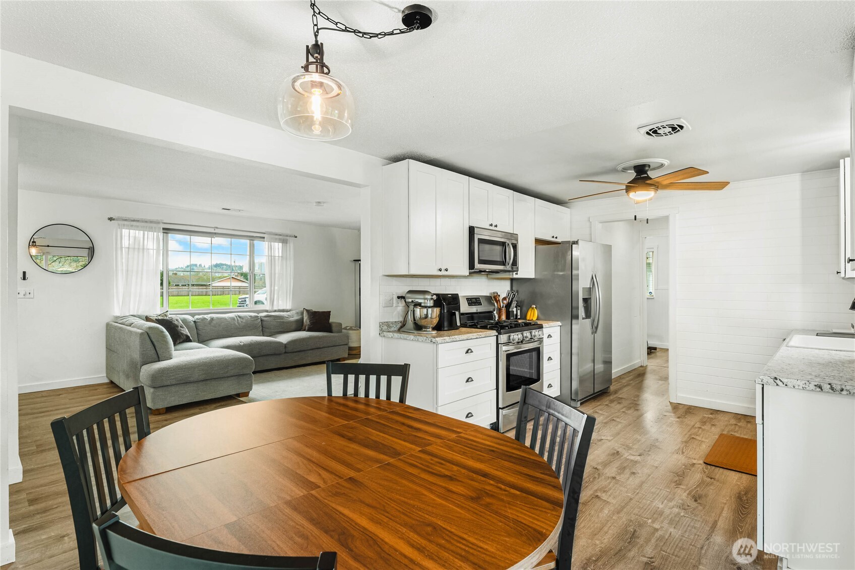 924 9th Street Southwest Puyallup, WA 98371 - Photo 15 of 38 a kitchen with stainless steel appliances kitchen island granite countertop a refrigerator a stove a sink dishwasher and white cabinets with wooden floor
