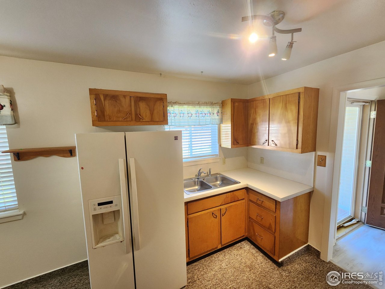 1107 Delmar Street Sterling, CO 80751 - Photo 19 of 49 a kitchen with stainless steel appliances granite countertop a refrigerator a stove and a sink with wooden floor