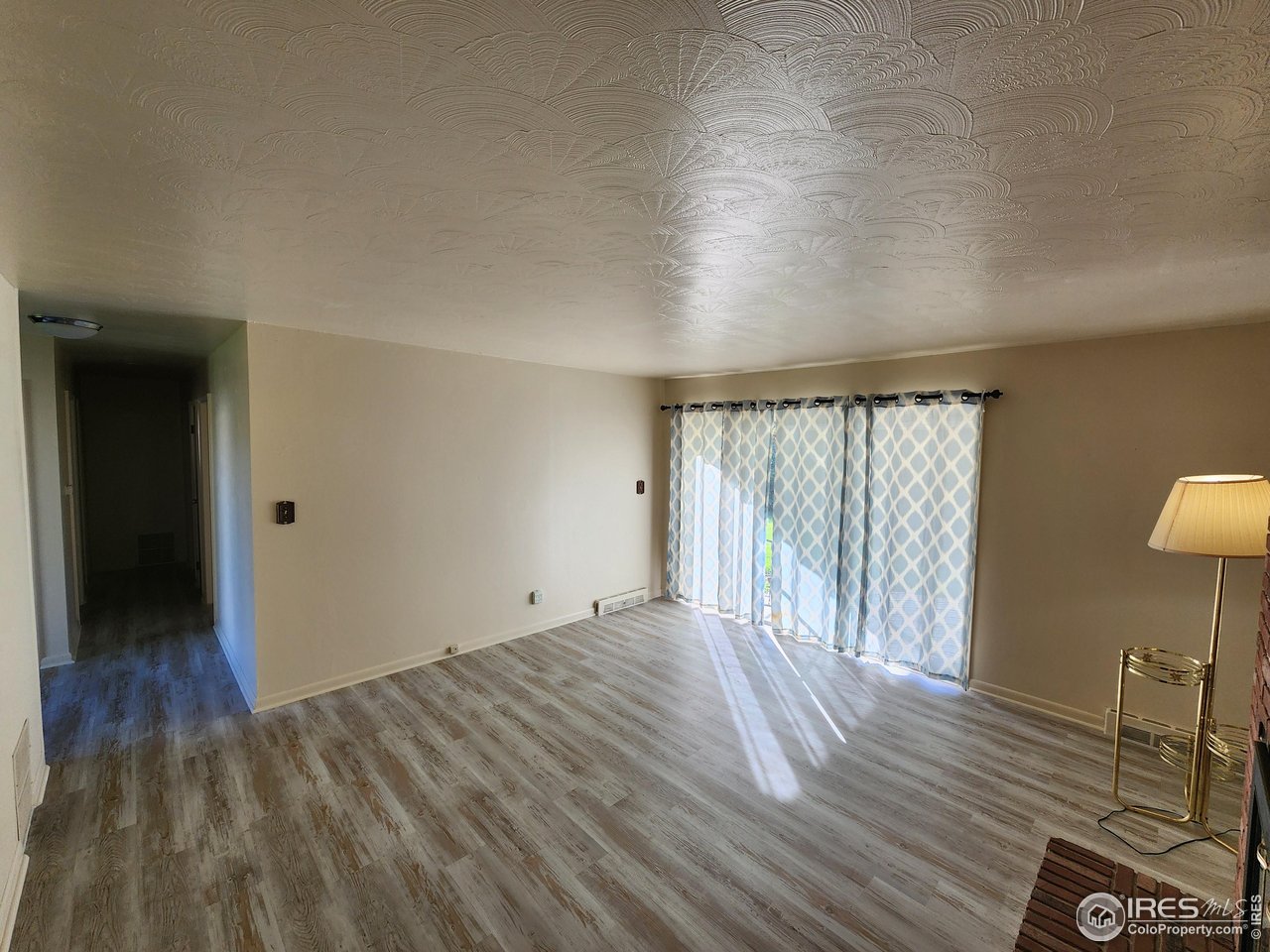 1107 Delmar Street Sterling, CO 80751 - Photo 6 of 49 a view of an empty room with wooden floor and a window