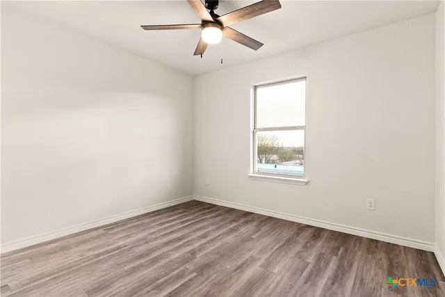an empty room with a window and a ceiling fan