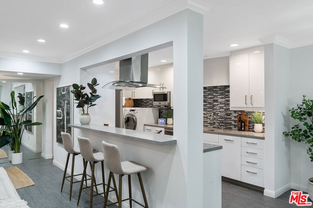 1015 North Kings Road, Unit 110 West Hollywood, CA 90069 - Photo 10 of 38 a kitchen with white cabinets and chair