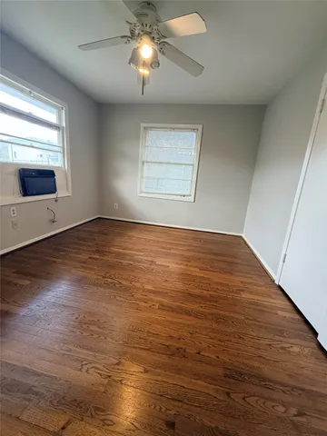 an empty room with wooden floor fan and windows