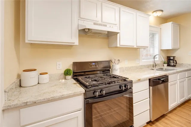 a kitchen with granite countertop a stove and a white sink