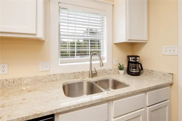 a kitchen with granite countertop a sink and a white wooden cabinets