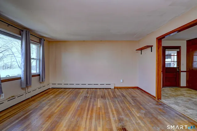a view of an empty room with wooden floor and a window