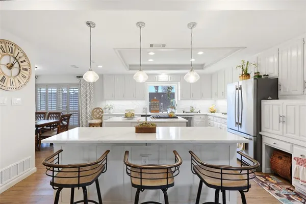 a kitchen with stainless steel appliances a dining table chairs and a refrigerator