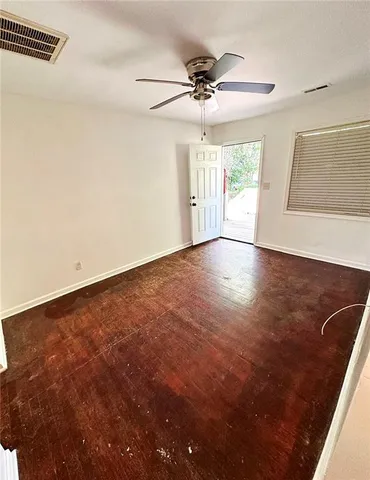an empty room with wooden floor fan and windows