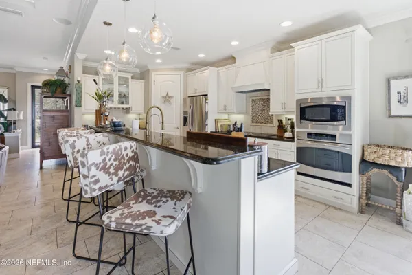 a kitchen with stainless steel appliances kitchen island granite countertop a stove top oven a sink a dining table and chairs