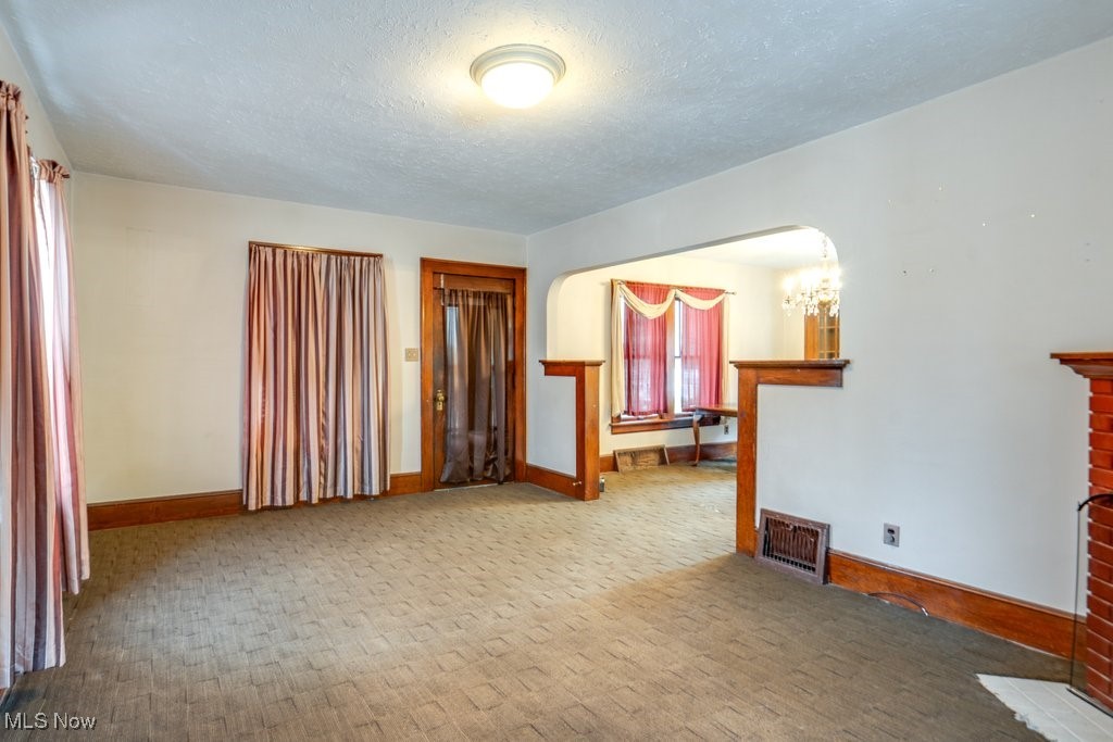 Carpeted living room featuring a chandelier and a textured ceiling