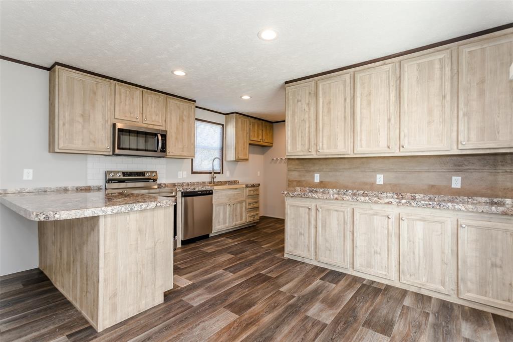 2900 Interstate 35, Unit 197 Waco, TX 76706 - Photo 3 of 24 a kitchen with granite countertop a stove top oven a sink dishwasher and a microwave oven with white cabinets