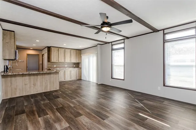 a view of kitchen with stainless steel appliances wooden floor large window and cabinets