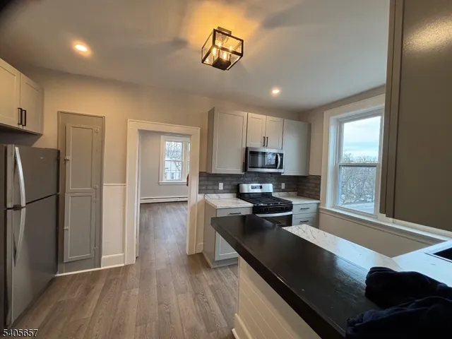 a kitchen with stainless steel appliances granite countertop a refrigerator a sink dishwasher a stove and a refrigerator with wooden floor