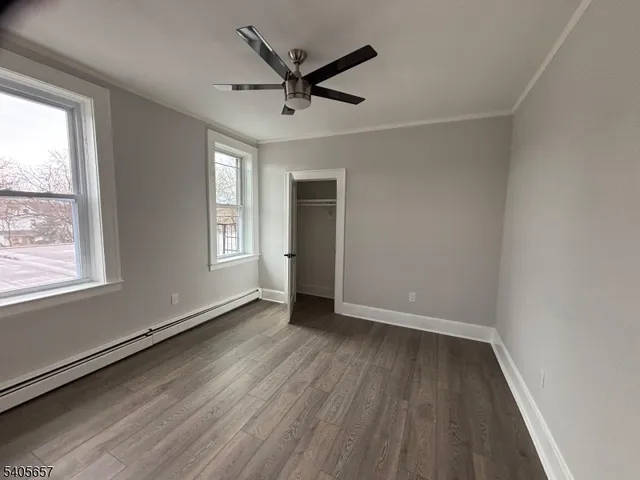 an empty room with wooden floor ceiling fan and windows