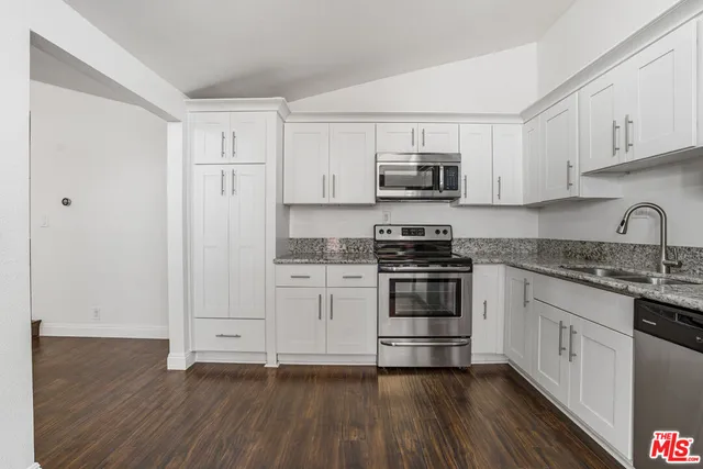 a kitchen with stainless steel appliances granite countertop a stove and white cabinets