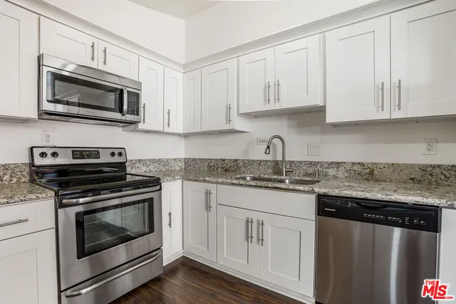 a kitchen with granite countertop white cabinets and stainless steel appliances