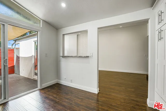 a view of an empty room with wooden floor and a bathroom