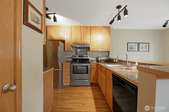 a kitchen with stainless steel appliances granite countertop a refrigerator a stove and a sink