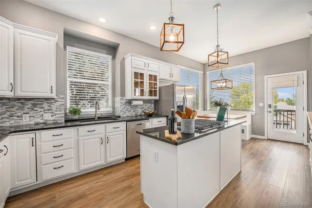 a kitchen with granite countertop a sink a counter space appliances and cabinets