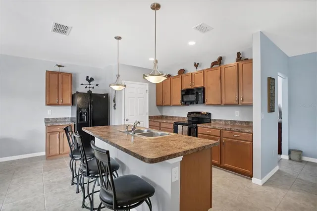 a kitchen with stainless steel appliances granite countertop a sink a stove a refrigerator a dining table and chairs with wooden floor