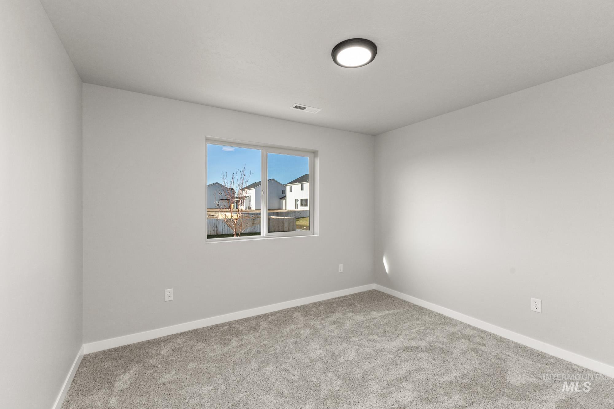 436 Merlin Court Middleton, ID 83644 - Photo 9 of 20 Bright room featuring a large window, neutral gray carpeting, white baseboards, and a contemporary ceiling light fixture