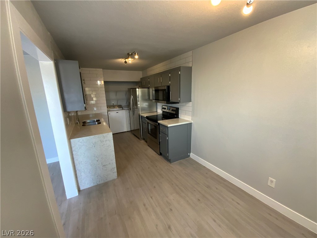 466 East Sunset Road, Unit C Henderson, NV 89011 - Photo 2 of 12 Kitchen with light countertops, light wood-style floors, tasteful backsplash, and appliances with stainless steel finishes