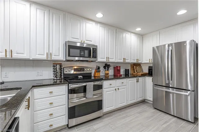 a kitchen with granite countertop white cabinets and stainless steel appliances