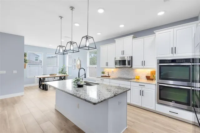 a kitchen with stainless steel appliances granite countertop a sink a stove and cabinets