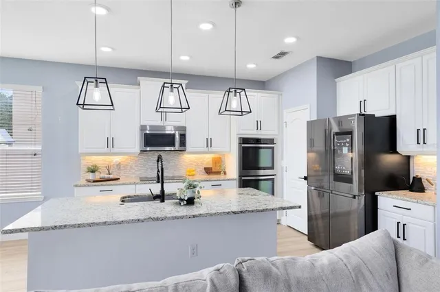 a kitchen with stainless steel appliances granite countertop a refrigerator and a sink